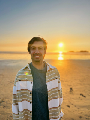 A man smiling and posing for a photo on a beach