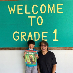 Andy Ho posing with a young student, showing a book