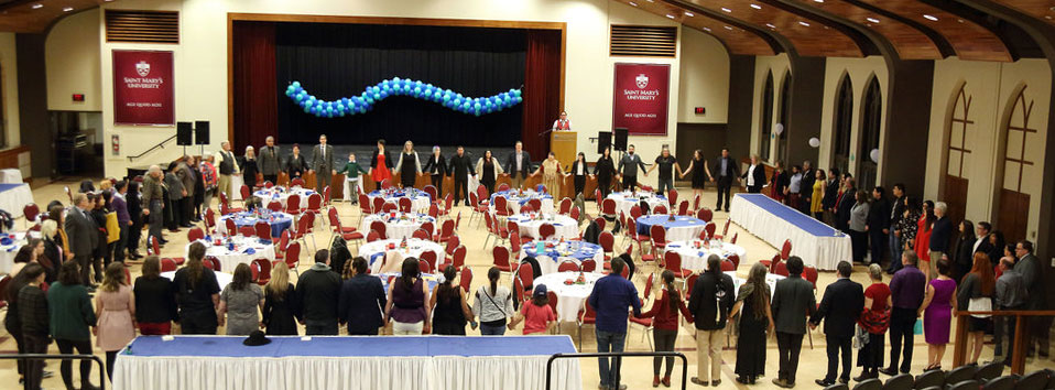 Members of the university community standing in a circle at an Indigenous celebration.