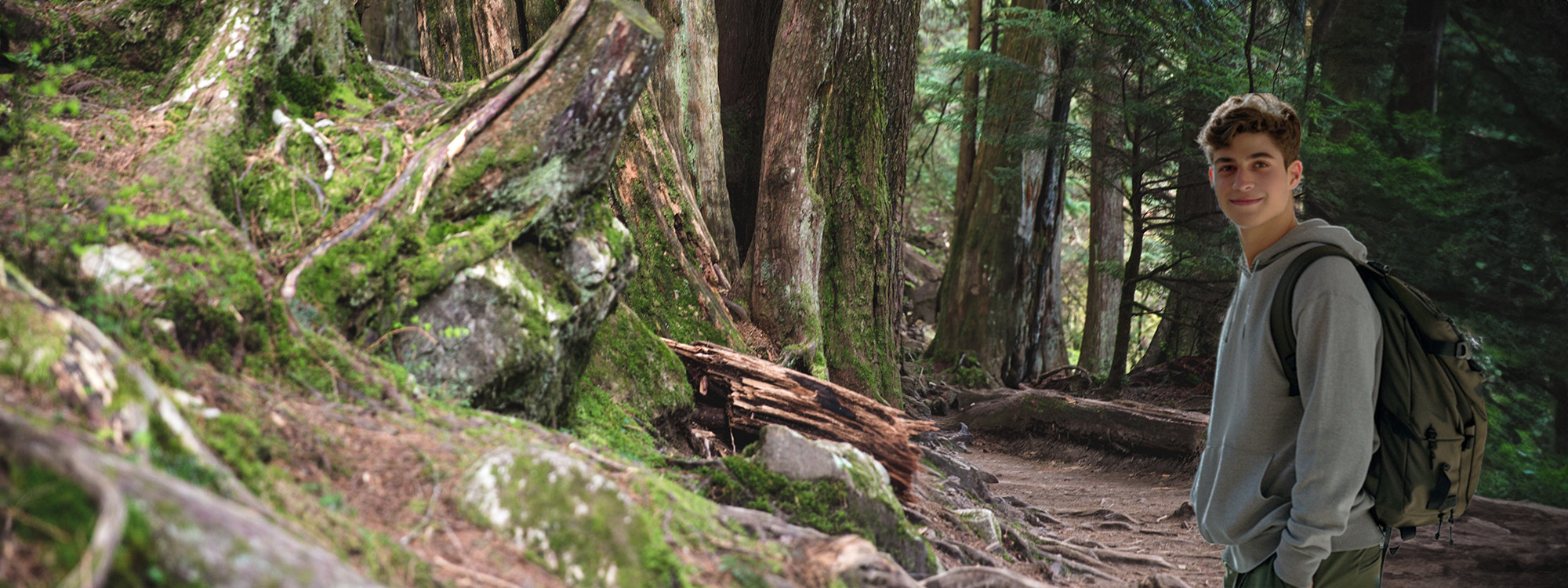 A young man wearing a backpack on a forest path.